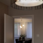 Lampa wisząca Estera w beżowej kolorystyce z jasnym drewnem, z trzema oprawami G9. Produkt zawieszony w pomieszczeniu, z widocznymi kulistymi źródłami światła, na tle okna z firanami i stół z rośliną.
