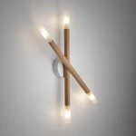 Lampa sufitowa Noble 4xG9 w jasnym drewnie, z dwoma krzyżującymi się elementami. Każdy z nich zakończony jest przezroczystym kloszem, emitującym ciepłe światło. Montaż na ścianie, na tle jasnej powierzchni.