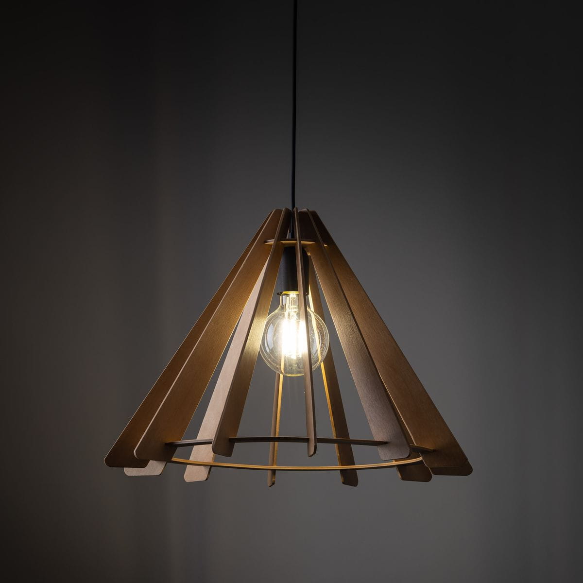 Lampa wisząca Eris z kloszem w kształcie stożka, wykonanym z jasnego drewna. Wyposażona w żarówkę E27, zawieszona na czarnym przewodzie. Widoczna szklana żarówka, emitująca ciepłe światło, w minimalistycznym stylu. Tło ciemne.