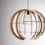 Lampa wisząca Venus L w kolorze czarnym i jasnego drewna, z okrągłą, ażurową konstrukcją. Zawiera żarówkę E27, widoczną w centralnej części. Ujęcie z boku, ukazujące detale drewna i otwarte przestrzenie. Tło jasne, minimalistyczne.