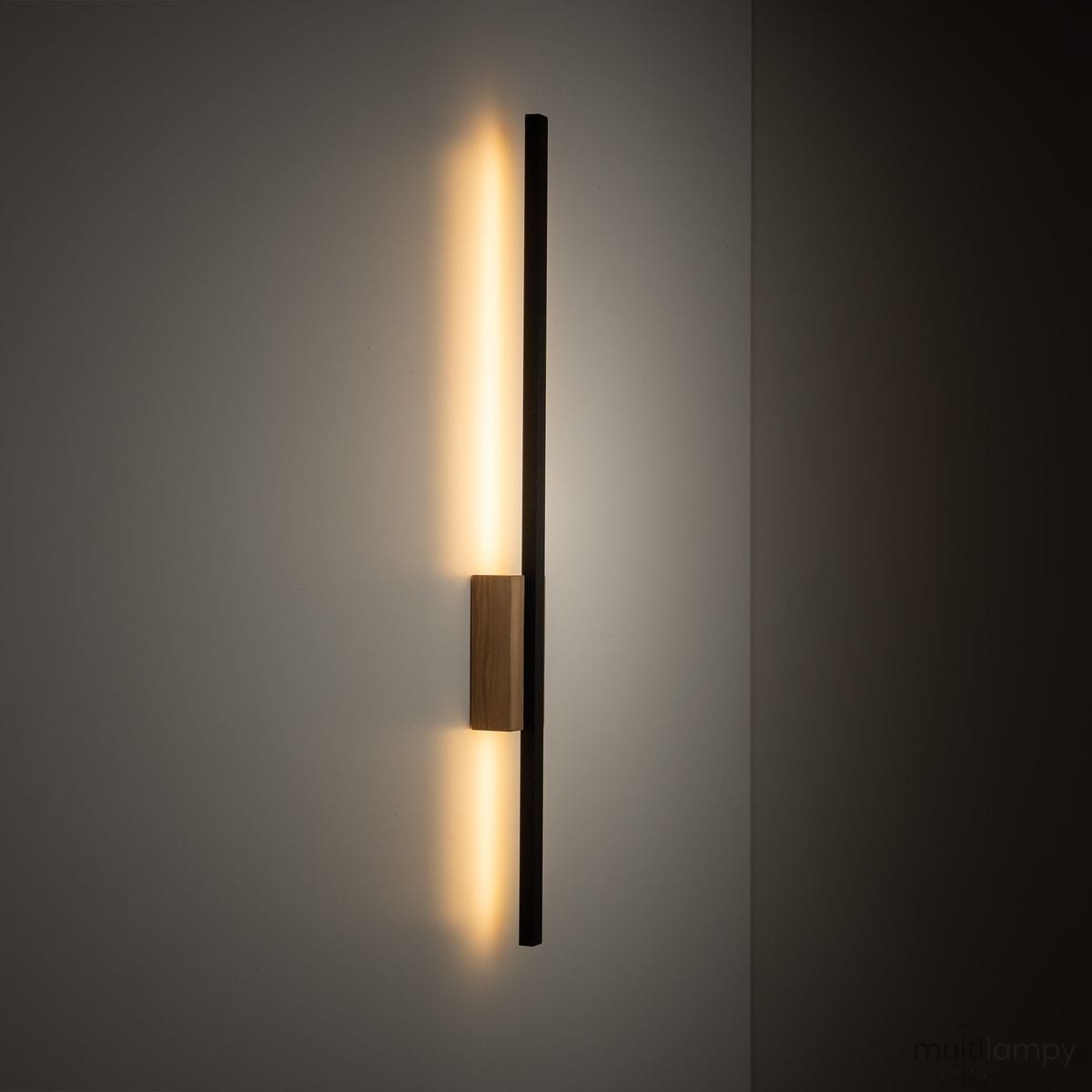 Kinkiet Flash M z jedną diodą LED o mocy 12W, w kolorze czarnym z elementami jasnego drewna. Produkt zamontowany na ścianie, emitujący ciepłe światło. Prosty, nowoczesny kształt, z widocznym drewnianym mocowaniem centralnym.