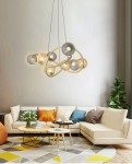 Lampa wisząca Metz w kolorze złotym z 8 źródłami światła G9, o nowoczesnym, organicznym kształcie. Zawieszona na cienkich linkach, z różnokolorowymi kloszami, tworzy efektowne źródło oświetlenia w stylowym wnętrzu.