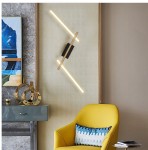 Czarna lampa sufitowa Rimini z trzema źródłami LED o mocy 40W, umieszczona na ścianie w nowoczesnym wnętrzu. Proste, geometryczne kształty i ciepłe światło, w otoczeniu żółtego fotela i dekoracji.
