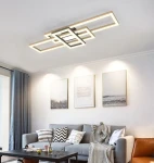 Czarna lampa sufitowa Matera z 4 żarówkami LED, o nowoczesnym, geometrycznym kształcie. Ujęcie z dołu, montowana na suficie, emituje ciepłe światło, idealna do aranżacji wnętrz. W tle widoczny salon z sofą i obrazami na ścianie.