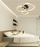 Lampa sufitowa Perpignon z trzema okrągłymi źródłami LED w kolorze czarnym i złotym, zamontowana na suficie. Widok z dołu, w nowoczesnej sypialni z jasnymi ścianami i minimalistycznym wystrojem.