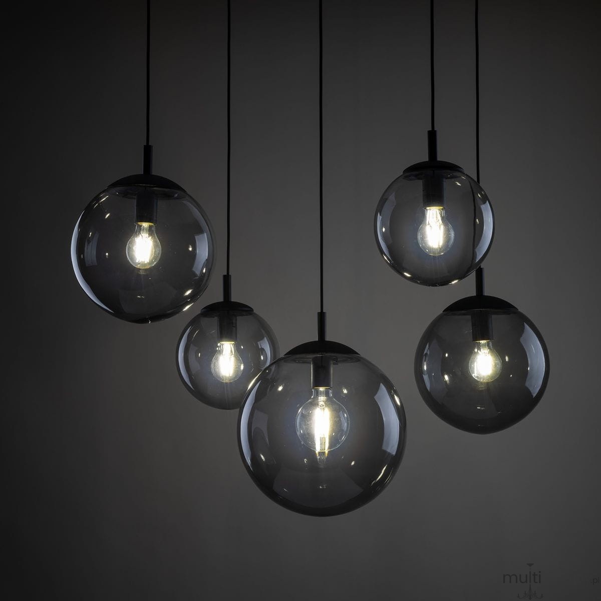 Lampa wisząca Esme z pięcioma kulistymi kloszami w kolorze czarnym i grafitowym, zawieszona na cienkich linkach. Klosze wykonane z przezroczystego szkła, w środku widoczne żarówki E27, na szarym tle.