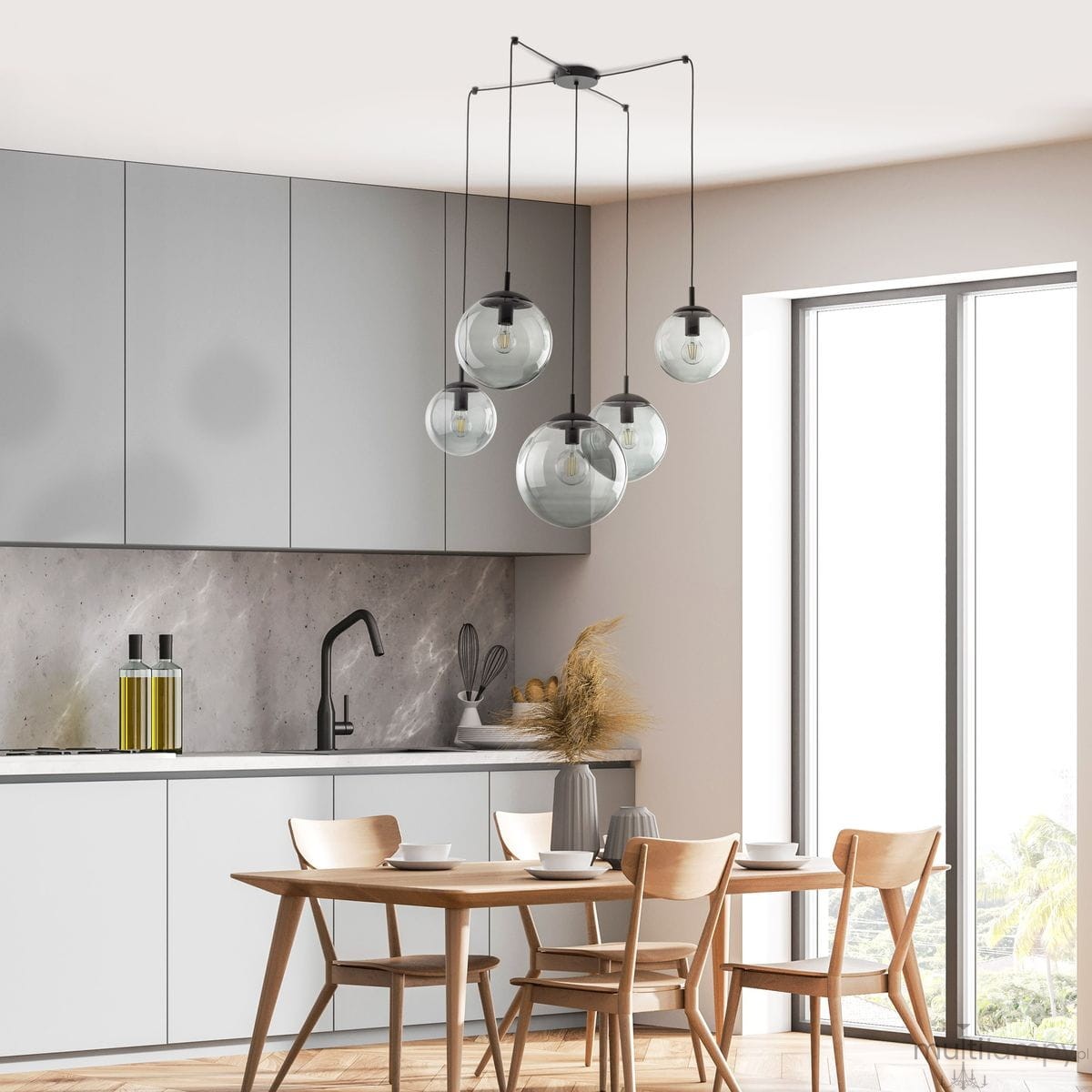 Lampa wisząca Esme 5xE27 w kolorze czarnym i grafitowym, z pięcioma szklanymi kloszami w różnych rozmiarach, zawieszona na cienkich kablach. Ujęcie z góry, w nowoczesnej kuchni z jasnymi meblami i drewnianym stołem.