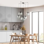 Lampa wisząca Esme 5xE27 w kolorze czarnym i grafitowym, z pięcioma szklanymi kloszami w różnych rozmiarach, zawieszona na cienkich kablach. Ujęcie z góry, w nowoczesnej kuchni z jasnymi meblami i drewnianym stołem.