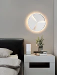 Lampa sufitowa Trapani D49 w chromie z jedną diodą LED 40W, o okrągłym kształcie z trzema białymi panelami, emituje ciepłe światło. Zawieszona na szarej ścianie nad łóżkiem, w nowoczesnym wnętrzu.