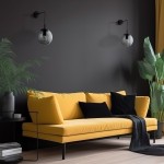 Kinkiet Esme 1xE27 w kolorze czarnym i grafitowym, zamontowany na ciemnej ścianie. Obok żarówki znajduje się przezroczysta kula. W tle żółta sofa z czarnymi poduszkami oraz rośliny dekoracyjne na stoliczku.