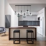 Lampa wisząca Esme w kolorze czarnym i grafitowym, z sześcioma szklanymi kloszami. Zawieszona nad wyspą kuchenną, w nowoczesnym wnętrzu. Klosze mają okrągły kształt, a całość jest podwieszona na cienkich linkach.