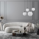 Lampa wisząca Esme z czarnymi i białymi elementami, cztery okrągłe klosze z matowego szkła, zwisające w różnych wysokościach. Zawieszona w nowoczesnym wnętrzu z jasną sofą i eleganckim stolikiem.