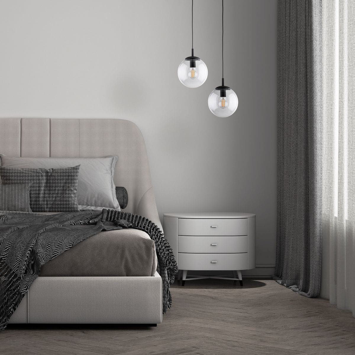 Lampa wisząca Esme D30 z jedną oprawą E27, czarna i transparentna. Dwa okrągłe klosze zawieszone na czarnych przewodach. Lampa umieszczona nad łóżkiem w nowoczesnej sypialni z szarym kocem i białą komodą.