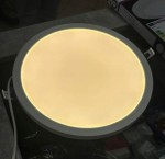 Panel LED D30 8w1/12-24W/3-4-6000K w kształcie okrągłym, natynkowy, biały, z delikatnym podświetleniem. Widok z góry, podłączony do zasilania, umieszczony na szarej powierzchni. Idealny do podtynkowej instalacji oświetleniowej.