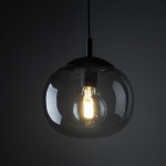 Lampa wisząca Vibe D25 z jedną oprawą E27 w kolorze czarnym i grafitowym, z przezroczystym kloszem, ukazującym żarówkę. Ujęcie z dołu, skupione na detalach konstrukcji i kształcie klosza. Tło ciemne, podkreślające elegancję lampy.