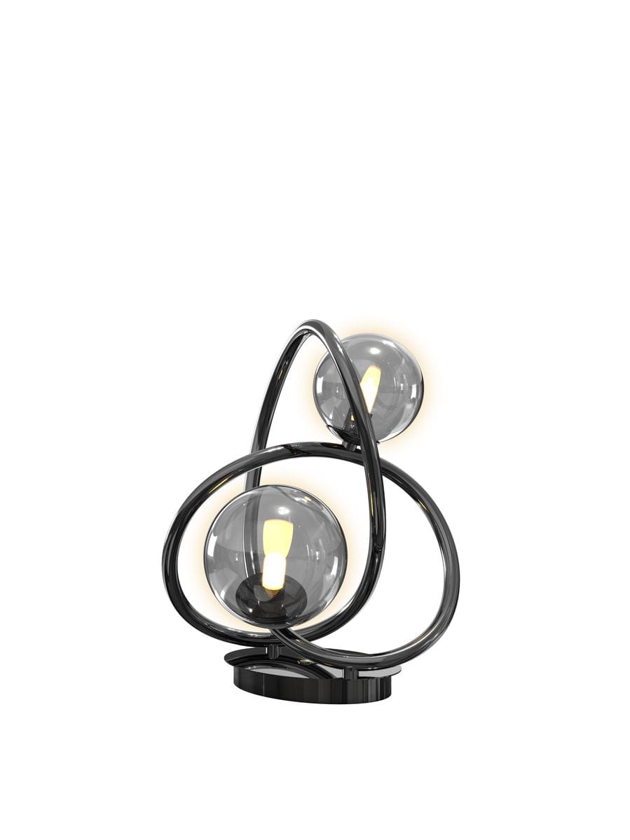 Lampa stołowa Nancy z dwoma żarówkami G9, w kolorze czarnym z chromowanymi detalami. Okrągła podstawa, złożona z dwóch zakrzywionych ramion, które podtrzymują dymione klosze. Ujęcie frontalne, lampa w pozycji stojącej.