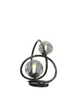 Lampa stołowa Nancy z dwoma żarówkami G9, w kolorze czarnym z chromowanymi detalami. Okrągła podstawa, złożona z dwóch zakrzywionych ramion, które podtrzymują dymione klosze. Ujęcie frontalne, lampa w pozycji stojącej.