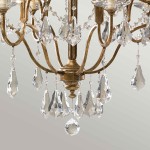 Lampa wisząca Valentina w oksydowanym brązie z sześcioma ramionami E14. Zdobiona kryształowymi wiszącymi elementami, w tym dużymi, łezkowatymi kryształami, tworzącymi elegancki efekt świetlny. Kąt ujęcia zbliżenie na detale.