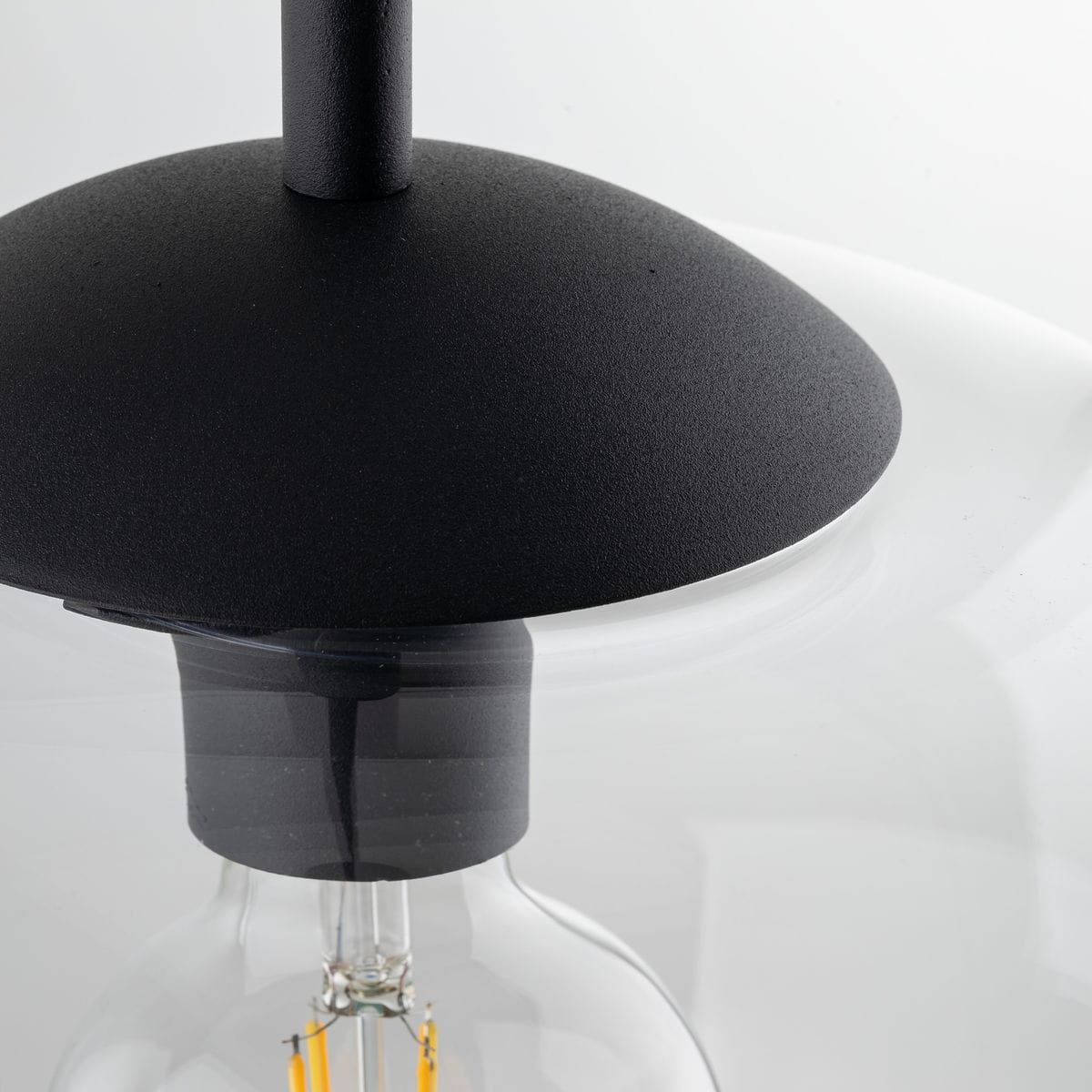 Czarna lampa wisząca Vibe D30 z transparentnym kloszem, z metalowym, matowym wykończeniem. Widoczny gwint E27 i elementy montażowe. Ujęcie z góry, ukazujące detale konstrukcji i połączenie klosza z podstawą.