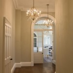 Lampa wisząca Gianna w postarzanym srebrze, z czterema gniazdami E14. Ozdobne ramiona z kryształkami, zawieszona w eleganckim wnętrzu. Widok frontalny, w tle jasne ściany i drzwi do pomieszczenia.