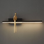 Kinkiet Amici 1xLED/5W w kolorze czarnym z mosiężnym detalem, z postacią siedzącą jako dekoracyjnym elementem. Montowany na ścianie, z dolnym podświetleniem LED, na jednolitym tle.