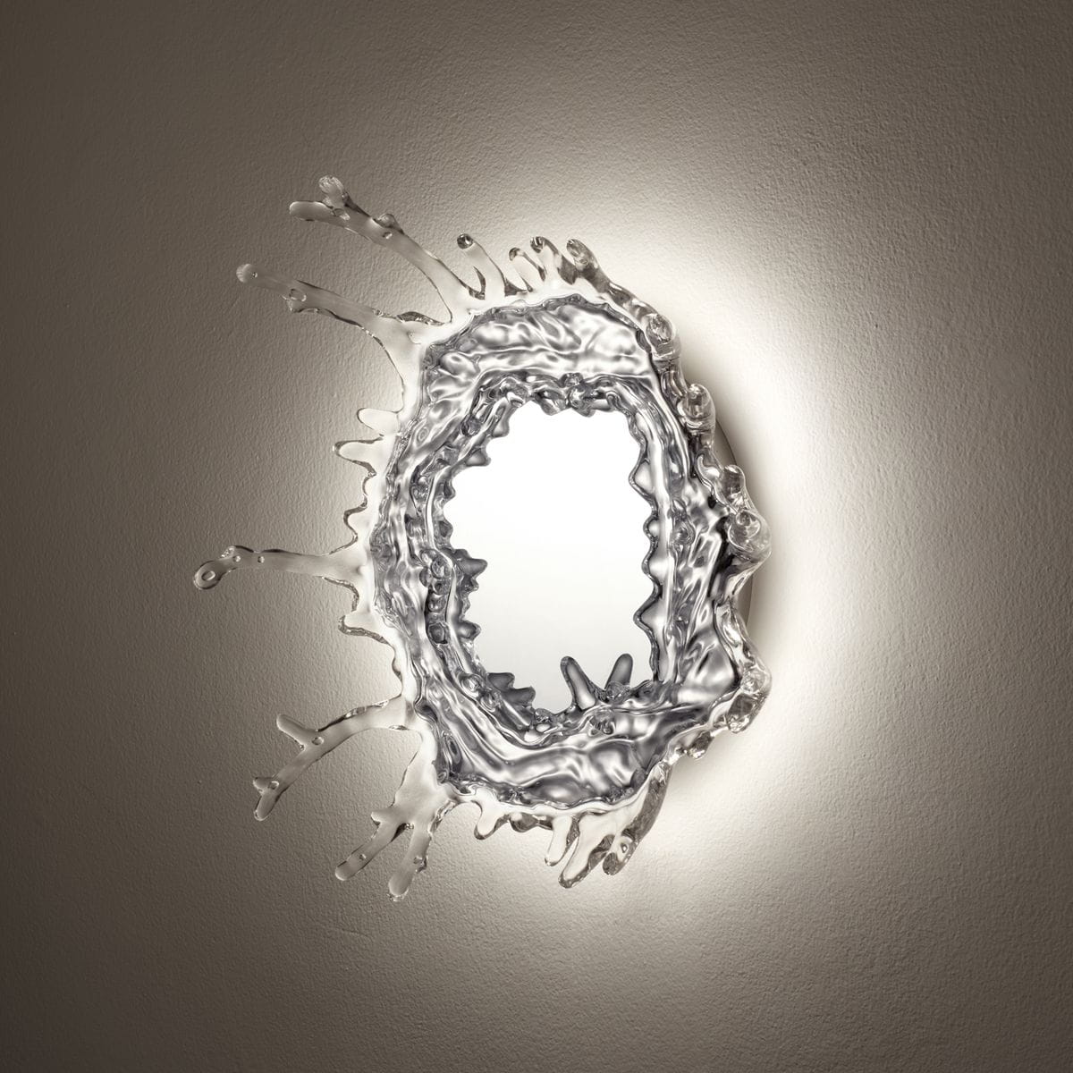 Lampa sufitowa Aqua D45 w kolorze chromu z elementami przypominającymi wodne krople. Owalny kształt z lustrzanym wnętrzem, emitująca światło LED o mocy 7W. Umieszczona na jasnej ścianie, podkreślająca nowoczesny styl wnętrza.