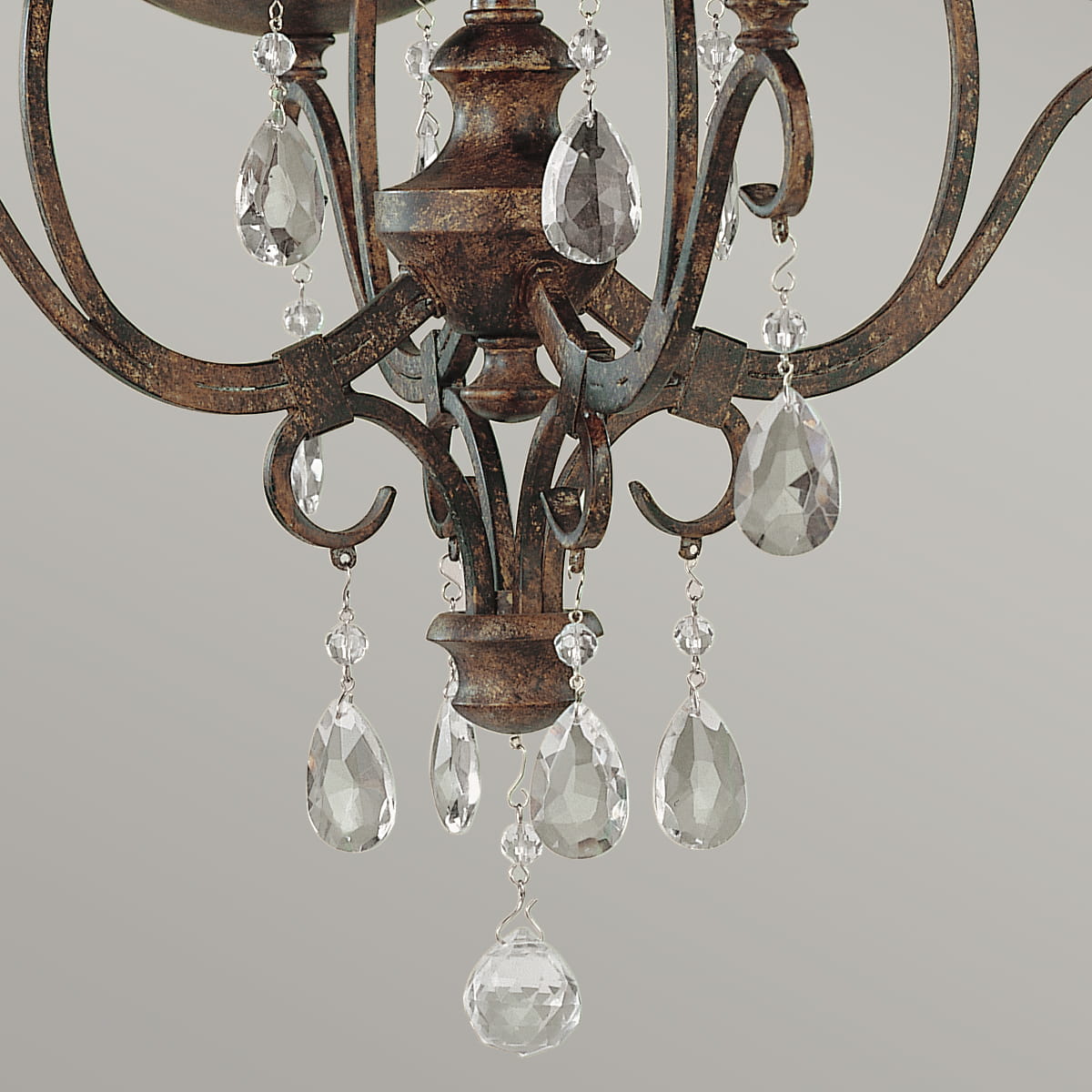 Lampa wisząca Chateau w brązowym, postarzanym wykończeniu, z czterema miejscami na żarówki E14. Ozdobiona kryształowymi wiszącymi elementami w kształcie kropli, dodającymi elegancji. Ujęcie zbliżeniowe na detale lampy.