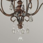 Lampa wisząca Chateau w brązowym, postarzanym wykończeniu, z czterema miejscami na żarówki E14. Ozdobiona kryształowymi wiszącymi elementami w kształcie kropli, dodającymi elegancji. Ujęcie zbliżeniowe na detale lampy.