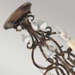 Lampa wisząca Chateau w kolorze brązowym postarzanym, z czterema miejscami na żarówki E14. Ozdobiona przezroczystymi kryształkami w kształcie kropli, z eleganckimi, zakrzywionymi elementami metalowymi. Ujęcie z góry, podkreślające detale konstrukcji.