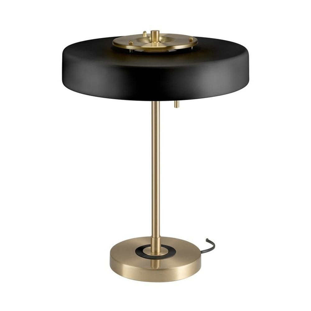 Lampa stołowa Artdeco z trzema gniazdami E14, w kolorze złotym szczotkowanym i czarnym. Okrągła podstawa, smukły stelaż, czarny abażur. Ujęcie z boku, prezentujące detale konstrukcji oraz włącznik. Tło neutralne, podkreślające elegancję lampy.