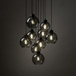Lampa wisząca Cubus z dziewięcioma kulistymi kloszami w kolorze czarnym i grafitowym, zawieszona na długich kablach. Klosze mają przezroczyste, szare szkło, a w ich wnętrzu znajdują się żarówki E27, emitujące ciepłe światło.