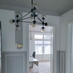 Lampa wisząca Astrifero z 10 miejscami na żarówki E27, w kolorze czarnym z transparentnymi kloszami. Ujęcie z dołu, zawieszona na cienkim przewodzie, w nowoczesnym wnętrzu z jasnymi ścianami i widokiem na okno.