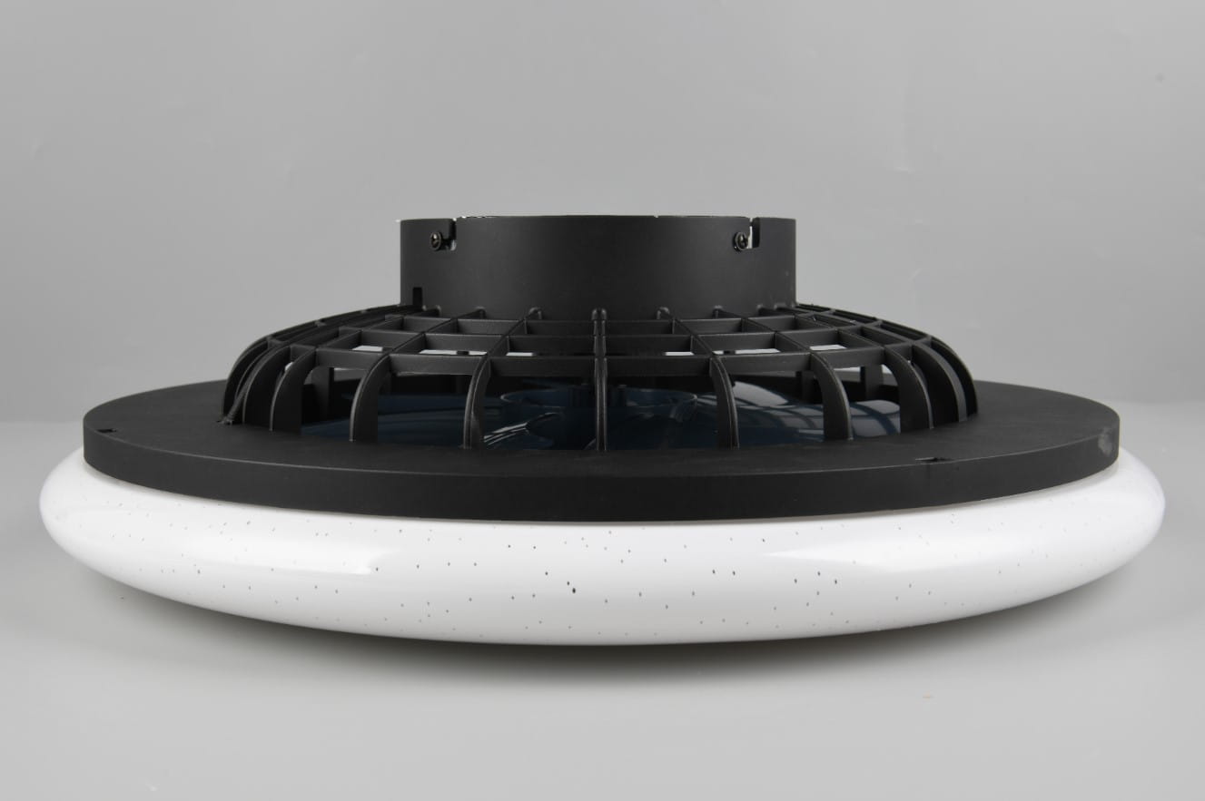 Biała lampa sufitowa Stralsund z wentylatorem, z czarną osłoną wentylatora i pilotem. Posiada okrągłą, matową podstawę z drobnymi kropkami. Ujęcie z boku, pokazujące szczegóły konstrukcji i wentylatora.