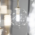 Lampa wisząca Aurora z 16 żarówkami G9, w czarnej i przezroczystej obudowie. W zbliżeniu widoczne szklane klosze oraz źródła światła, zawieszone na metalowej konstrukcji. Tło w odcieniu szarym, co podkreśla elegancję lampy.