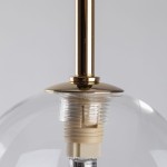 Lampa wisząca Aurora w kolorze czarnym i transparentnym, z metalowym uchwytem w złotym odcieniu. Widoczna oprawa dla żarówki G9 i przezroczysta kula, podkreślająca nowoczesny design. Ujęcie z góry, skupione na detalu mocowania i klosza.