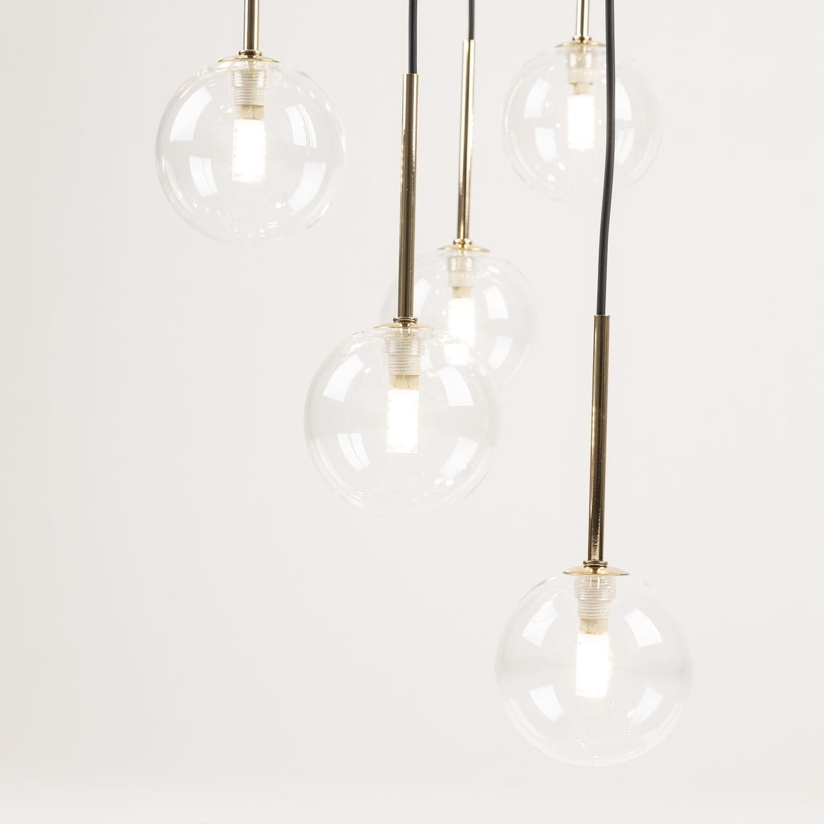 Lampa wisząca Aurora z sześcioma kulistymi kloszami z przezroczystego szkła na złotych metalowych podstawkach, zwisająca na czarnych przewodach. Klosze mają widoczne źródła światła G9. Tło jasne, jednolite.