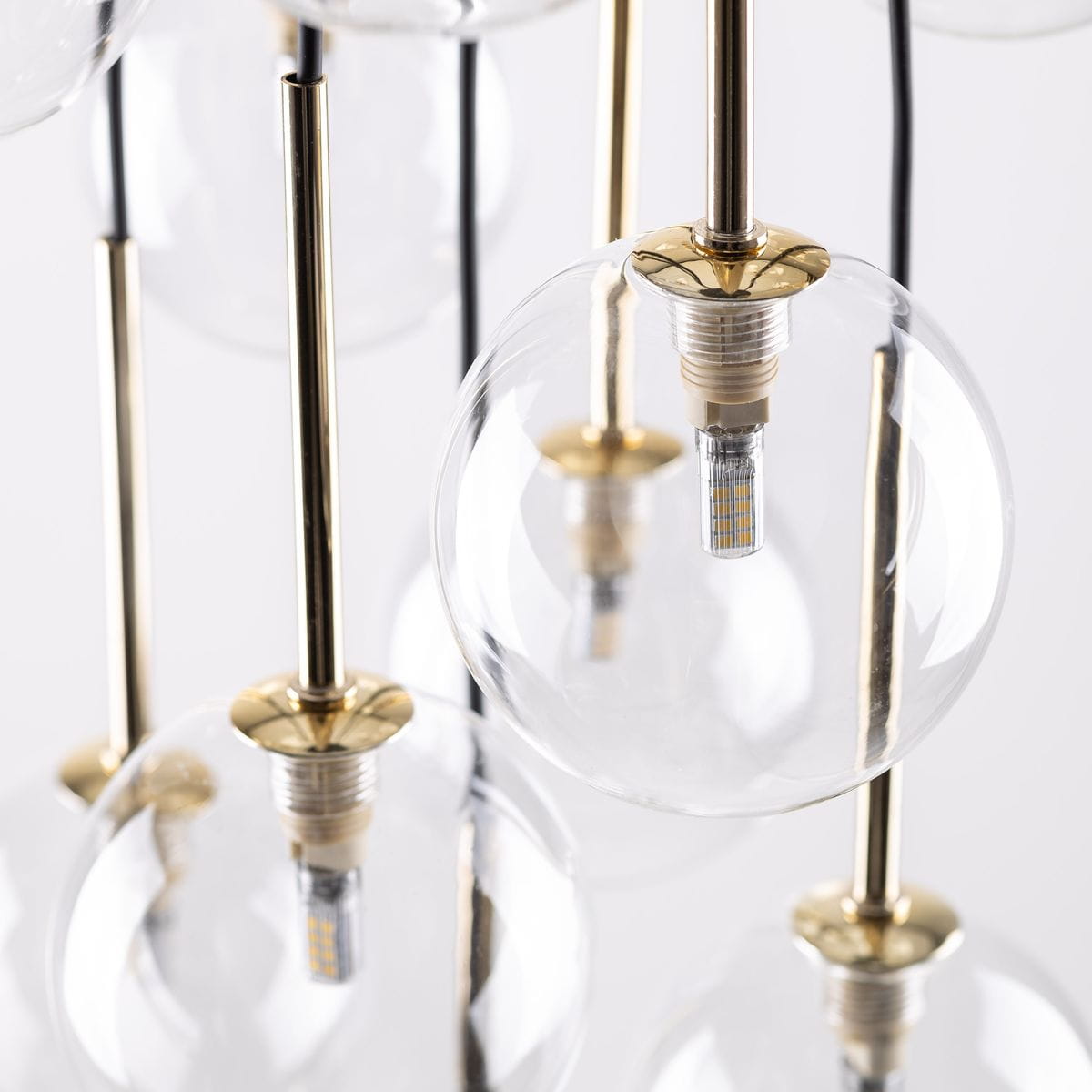 Lampa wisząca Aurora z 26 źródłami światła G9, w kolorze czarnym i przezroczystym. Eleganckie, szklane kuliste klosze zawieszone na złotych metalowych prętach, z widocznymi żarówkami LED wewnątrz.