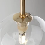 Lampa wisząca Nilos 1xG9 w kolorze czarnym i przezroczystym, z metalowym, złotym mocowaniem. Widoczne detale to kulisty klosz i źródło światła. Ujęcie z góry, ukazujące konstrukcję oraz połączenie klosza z zawieszeniem.