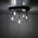 Lampa sufitowa Nilos z pięcioma kulistymi kloszami w przezroczystym kolorze, zamocowana na okrągłej czarnej podstawie. Wewnątrz kloszy znajdują się żarówki G9. Ujęcie z dołu, ukazujące szczegóły konstrukcji i źródła światła.