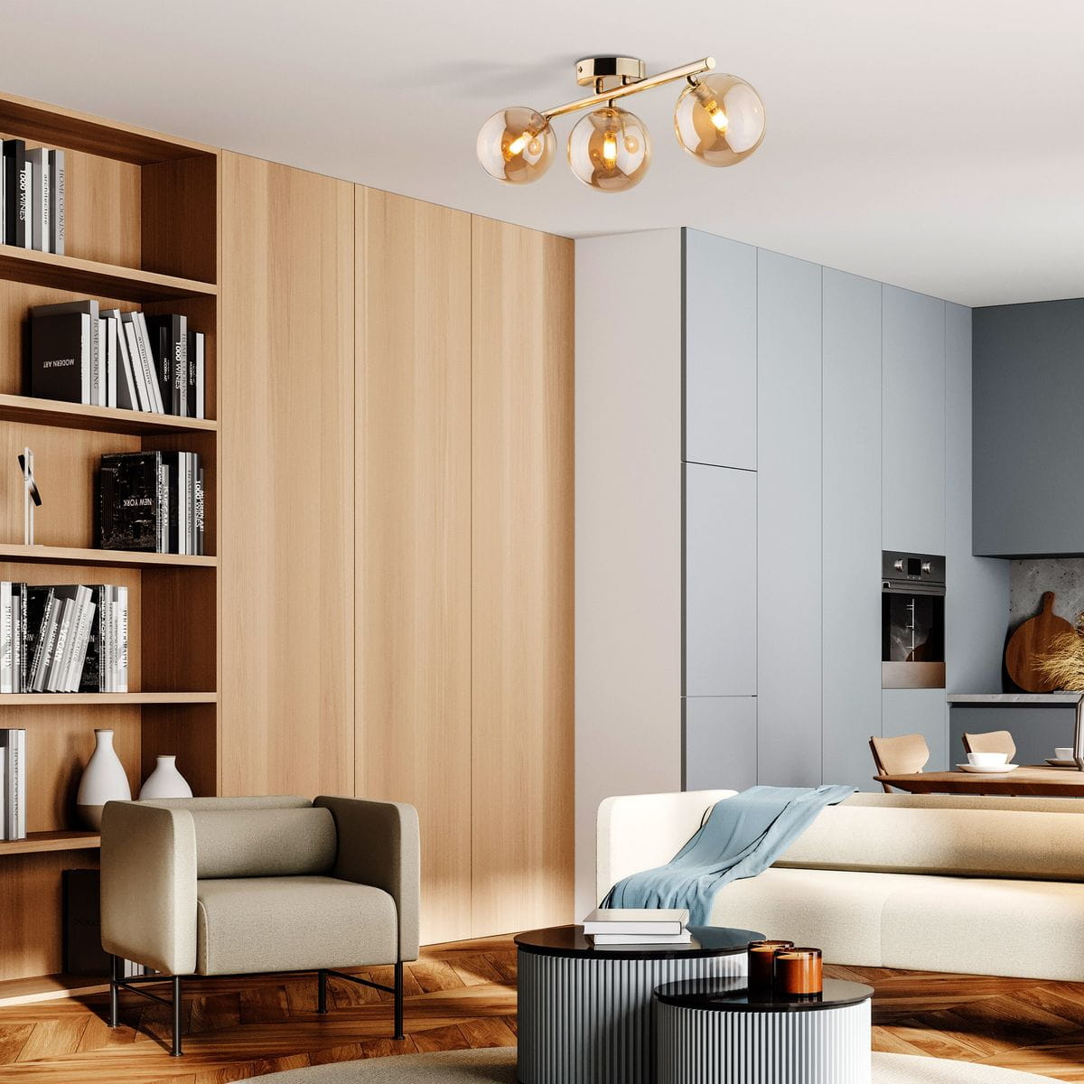 Lampa sufitowa Estera 3xG9 w złotym wykończeniu z bursztynowymi kloszami. Ułożona w formie trzech kul, montowana na metalowym stelażu. Widoczna w nowoczesnym wnętrzu z meblami w neutralnych kolorach, w otoczeniu drewnianej podłogi i regału.