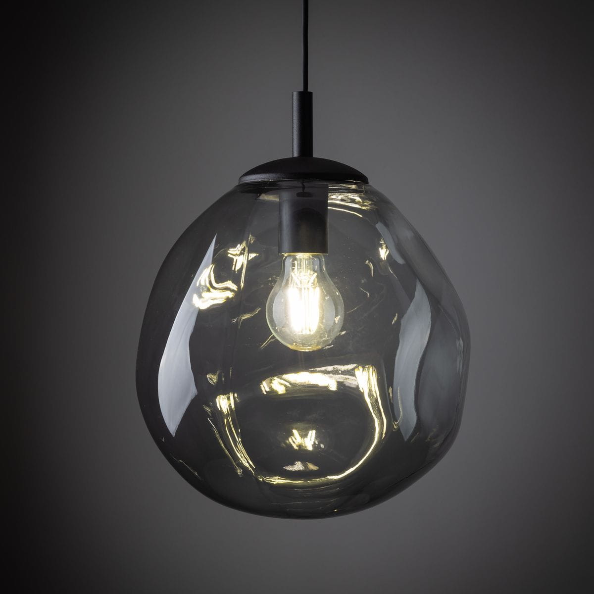 Lampa wisząca Sol D25 z kloszem w kształcie owalnym, wykonanym z przezroczystego szkła, z czarnym, matowym uchwytem. Widoczna żarówka E27 wewnątrz klosza. Produkt zawieszony na cienkim przewodzie, na ciemnym tle.