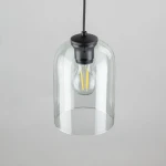 Lampa wisząca Molly w kolorze czarnym i zielonym, z przezroczystym kloszem, zawieszona na czarnym przewodzie. Wewnątrz widoczna żarówka E27 z widocznymi włóknami. Klosz ma okrągły kształt, a całość prezentuje nowoczesny design.