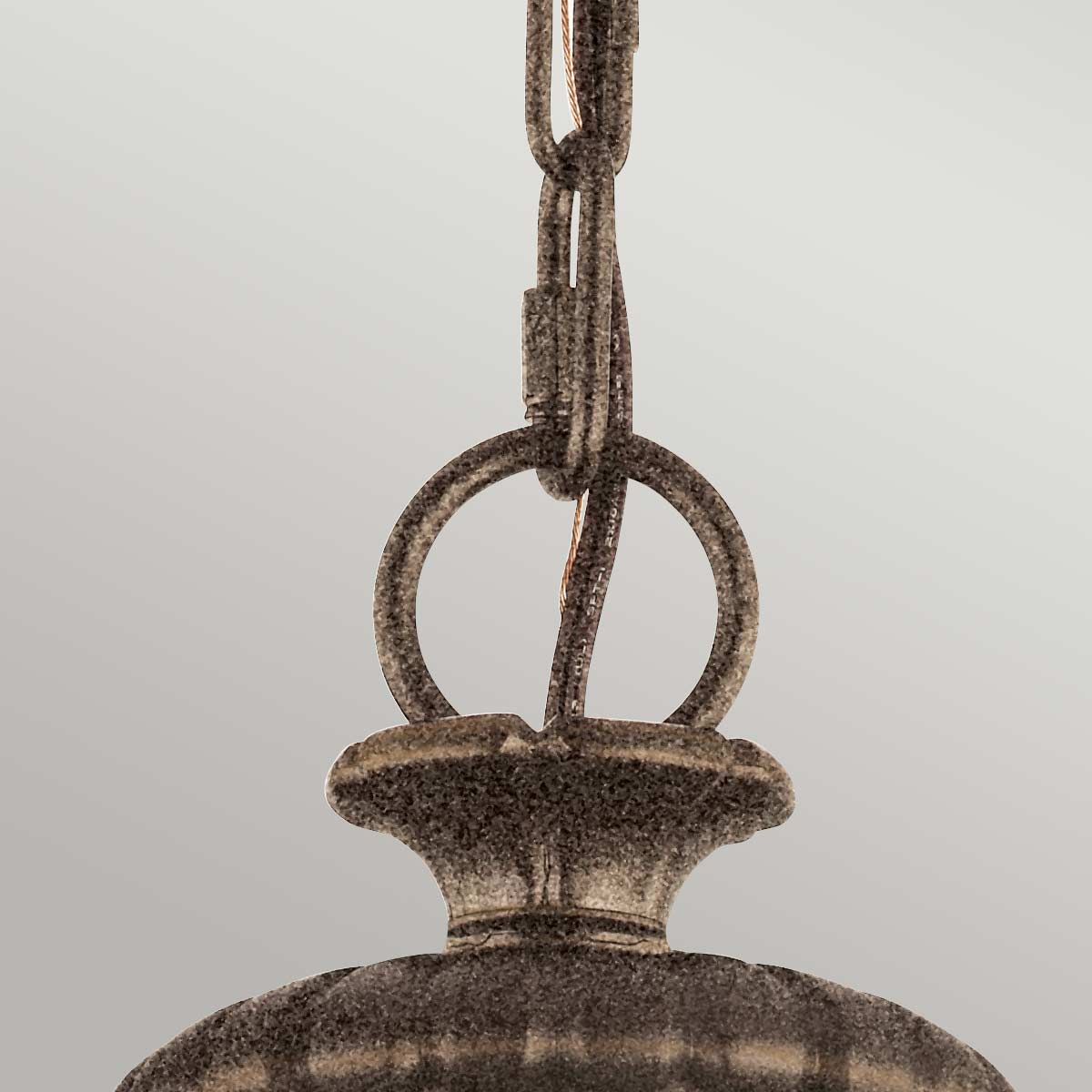 Lampa wisząca Adams 3xE14 w antycznym brązie, z okrągłym kloszem i metalowym zawieszeniem. Widoczny detal mocowania z okrągłym pierścieniem, który łączy kabel z lampą. Ujęcie z góry, na jednolitym tle.