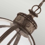 Lampa wisząca Adams w kolorze antycznego brązu z trzema oprawami E14. Widoczna metalowa podsufitka z dekoracyjnym wzorem oraz szklany klosz, zawieszona na łańcuchu, w ujęciu z góry.