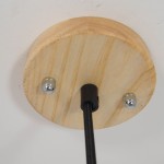 Ujęcie od dołu na mocowanie lampy wiszącej z szarym betonowym kloszem. Widoczne drewniane podłoże w kolorze jasnego drewna oraz czarny kabel. Elementy metalowe w kolorze srebrnym, mocowane na ścianie.