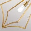 Lampa wisząca Nico XL z oksydowanego mosiądzu, z żarówką E27. Ujęcie z bliska, ukazujące złotą konstrukcję w kształcie liścia. Widoczny detal mocowania żarówki oraz refleks światła na metalowej powierzchni.