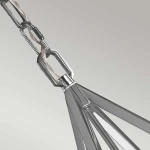 Lampa wisząca Nico XL w polerowanym chromie, z pojedynczym gwintem E27. Zbliżenie na element mocujący oraz linki. Kąt ujęcia ukazuje detale konstrukcji oraz połysk materiału. Tło w odcieniach szarości.