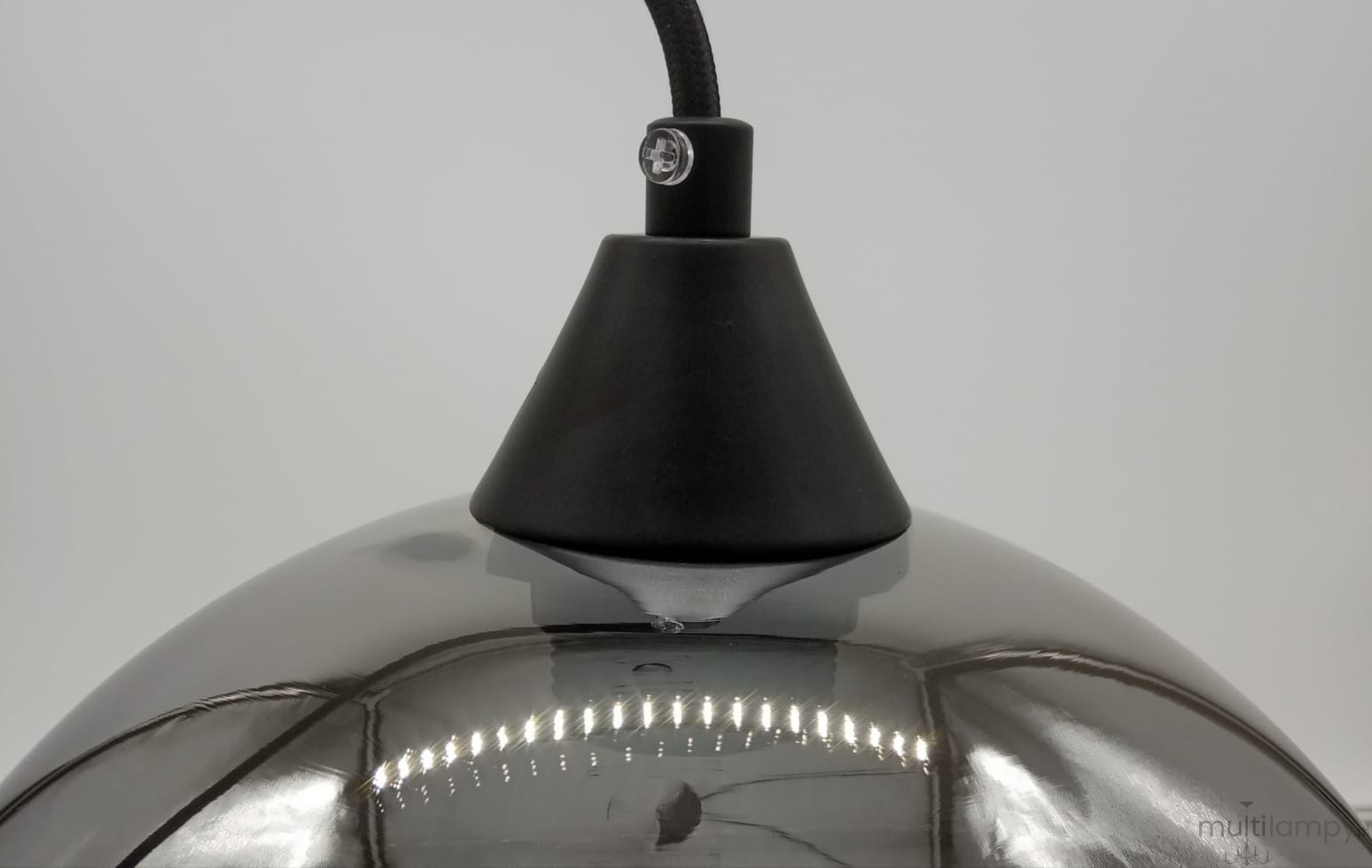 Lampa wisząca Love Bomb w kolorze czarnym i szarym z kloszem o kształcie półkuli. Ujęcie z bliska pokazuje czarny element mocujący oraz refleksy świetlne na szklanej powierzchni. Wtyk E27, idealna do nowoczesnych wnętrz.