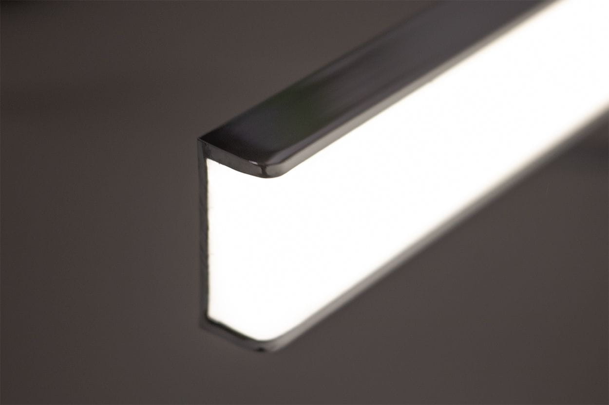 Kinkiet łazienkowy Venus LED IP44 w chromowanej obudowie, o prostokątnym kształcie. Widoczna biała luminiscencja wzdłuż krawędzi, lekko zaokrąglona. Ujęcie z boku, podkreślające detale wykończenia.