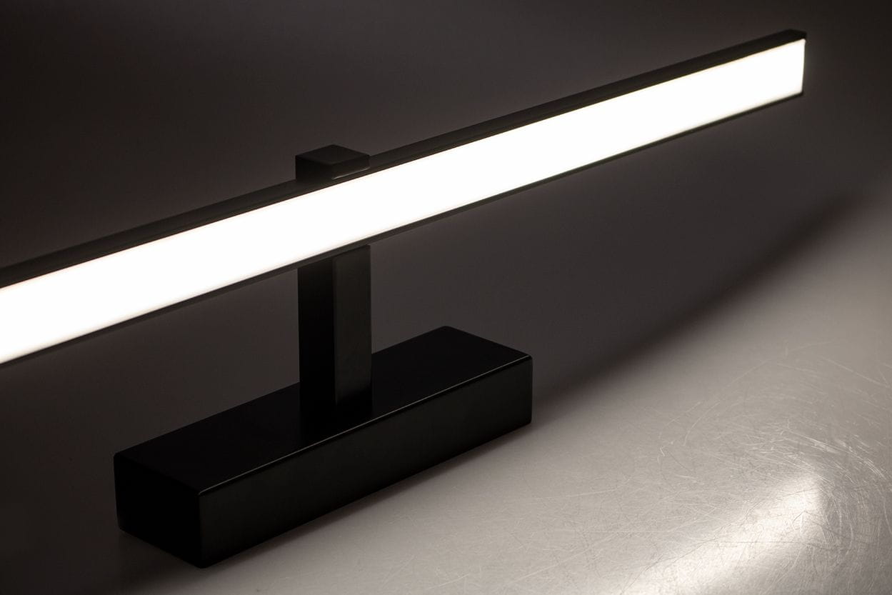 Czarny kinkiet łazienkowy Venus LED IP44, o długości 120 cm i mocy 24W. Prosty, prostokątny kształt z białym źródłem światła, umieszczony na stabilnej podstawie. Ujęcie pod kątem, akcentujące minimalistyczny design.